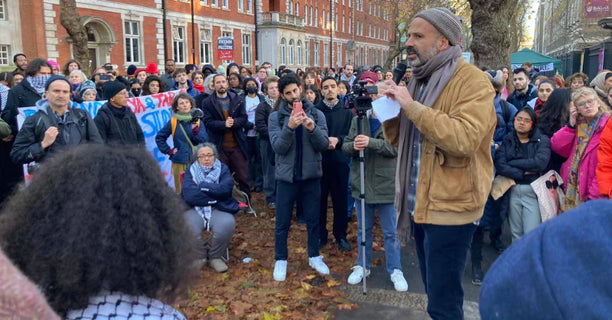 Toufic Haddad stands in a circle of students, speaking to them at a pro-Palestine rally.