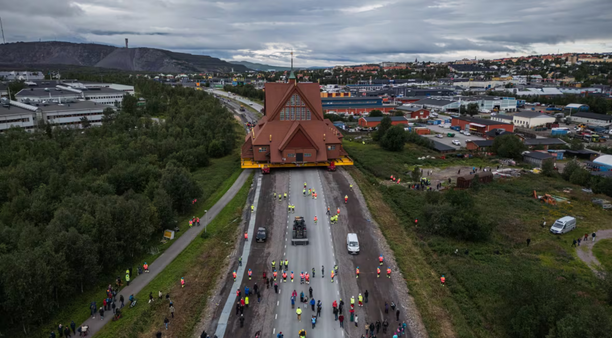 A church stands on a highway followed by a group of people
