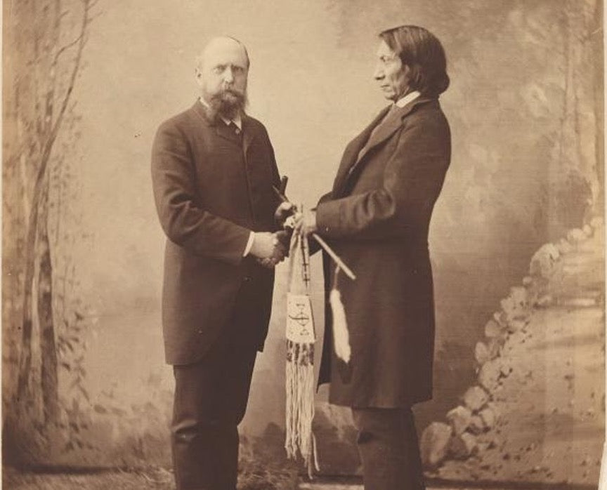 (The Oglala Lakota Chief Red Cloud posing for a photograph with Othniel Charles Marsh while holding a sacred pipe. Source: Image No. NPG.93.133, National Portrait Gallery, Smithsonian Institution.)