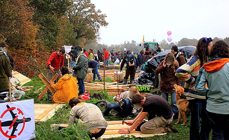Volunteers build cabins at the zad, November 2012. via Wikimedia Commons.