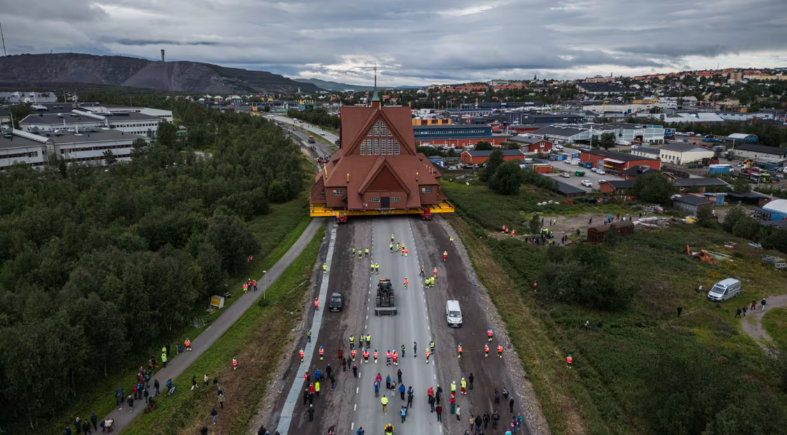 A church stands on a highway followed by a group of people